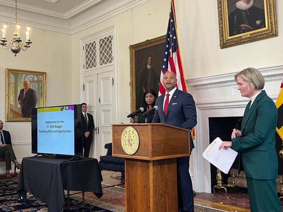 Standing beside Lt. Gov. Aruna Miller, left, and Helene Grady, the acting secretary of Budget & Management, Maryland Gov. Wes Moore on Monday called the 1,000-plus page budget document a “summation of our values.” A portrait of former Republican Governor Larry Hogan hangs on the wall, at far left.
