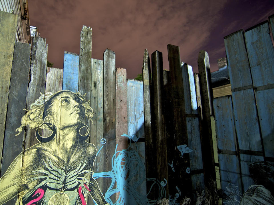 This undated photo provided by courtesy of New Orleans Airlift, shows a detail of Brooklyn street artist, Swoon's "Thalassa" print wheat-pasted on a section of fence in New Orleans. The fence sits outside the yard of Jay Pennington, the associate curator of The Music Box, a temporary community art project in New Orleans. The Music Box was phase one of the Dithyrambalina project--a permanent musical structure planned for the city. AP Photo/Courtesy New Orleans Airlift, Jay Pennington)