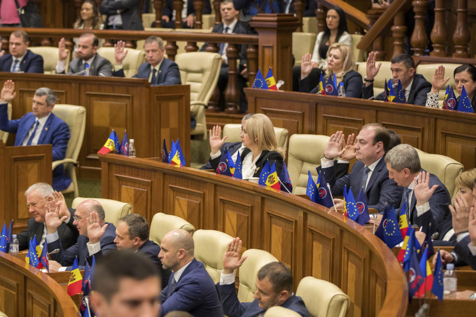 Moldovan members of parliament vote by raising their hands for a no-confidence motion against the government in Chisinau, Moldova, Tuesday, Nov. 12, 2019. Prime Minister Maia Sandu's government coalition between a pro-European group and a Russian-backed party has fallen after losing a no-confidence vote in parliament as 63 of 101 lawmakers supported the no-confidence motion. (AP Photo/Roveliu Buga)