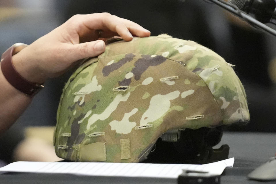 Nicole Herling, sister of shooter Robert Card, rests her hand on her brother's military helmet, while testifying, Thursday, May 16, 2024, in Augusta, Maine, during a hearing of the independent commission investigating the law enforcement response to the mass shooting in Lewiston, Maine. (AP Photo/Robert F. Bukaty)