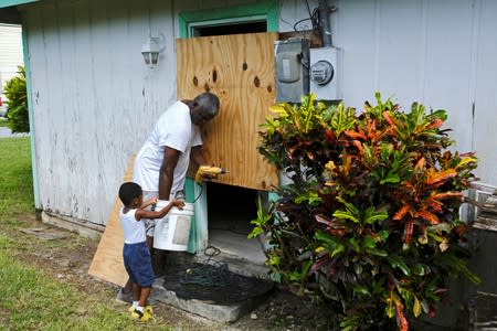 A small boy helps his father to secure a door before the arrival of Hurricane Dorian in Marsh Harbour