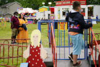 Alicia Duque, a 35-year-old mother of three and volunteer organizer for the progressive group, Action Together looks on with her husband Steve Edwards as their son Max waits to board a ride at the Edwardsville Pierogi Festival in Edwardsville, Pa., Friday, June 11, 2021. (AP Photo/Matt Rourke)