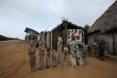 Woman arranges some of her arts and craft carvings that are for sale at the historic slave port of Ouidah