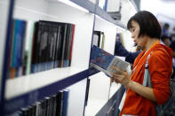 A woman looks at a book at the stall of Cambridge University Press (CUP) at the Beijing International Book Fair in Beijing, China, August 23, 2017. REUTERS/Thomas Peter