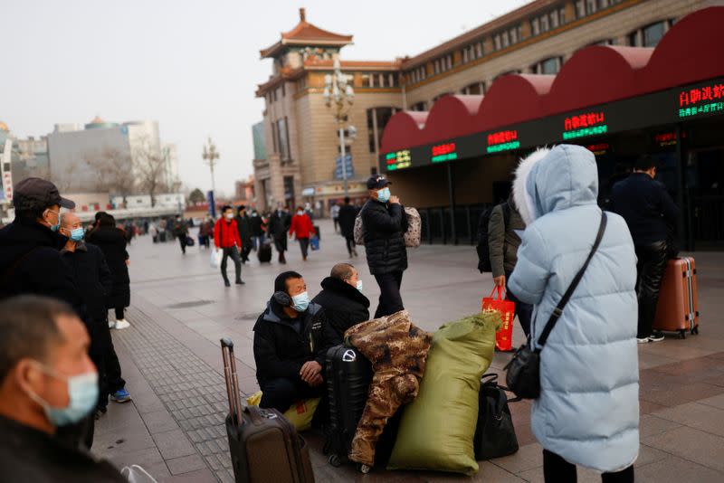 Migrant workers sit next to their belongings at a railway station in Beijing