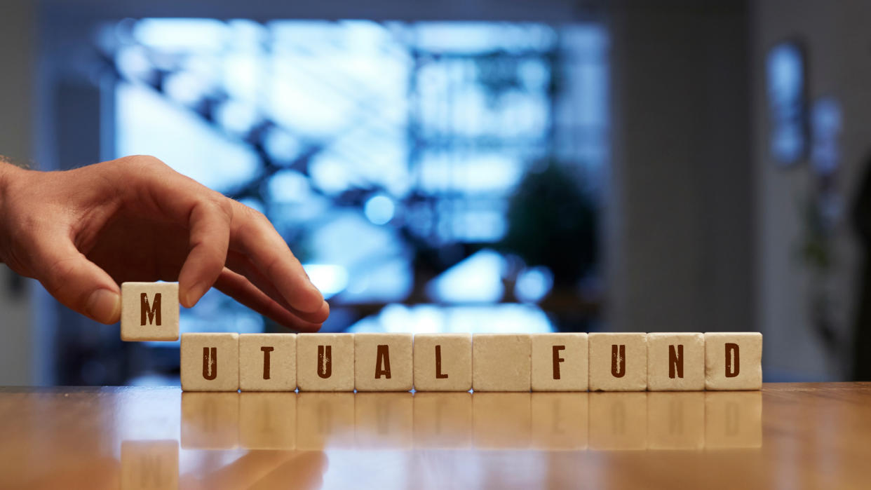 Mutual Fund Concept , Hand with alphabet blocks on wooden table.