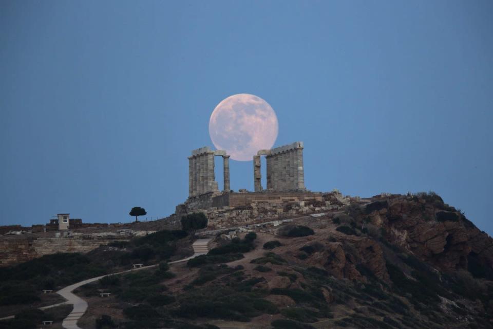 The full moon rises behind the columns of the ancient marble Temple of Poseidon at Cape Sounion, southeast of Athens, on the eve of the summer solstice on June 20, 2016. AP Photo/Petros Giannakouris)