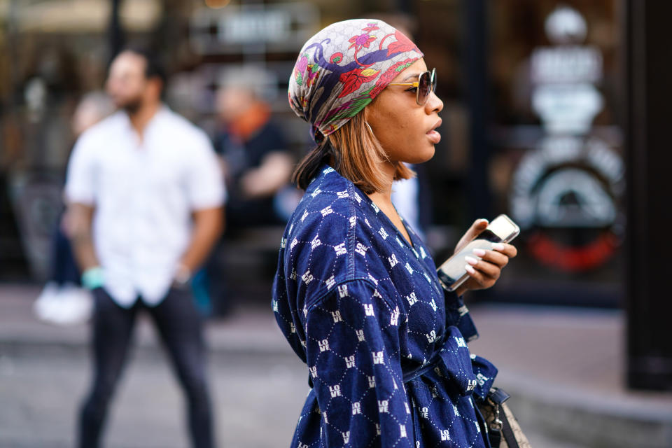 LONDON, ENGLAND - JUNE 08: A guest wears sunglasses, a colorful floral print hair scarf, a white word "love" design navy blue denim pantsuit , during London Fashion Week Men's June 2019 on June 08, 2019 in London, England. (Photo by Edward Berthelot/Getty Images)