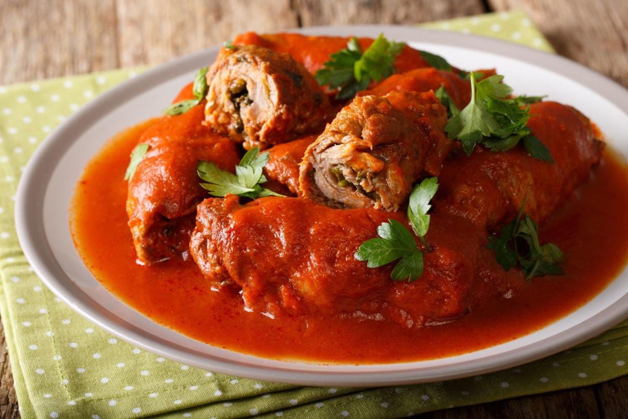 Delicious beef steak stuffed with parsley and parmesan cheese stewed in tomato sauce close-up on a plate. horizontal