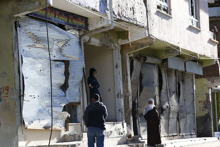 Residents stand in front of closed shops which were damaged during the security operations and clashes between Turkish security forces and Kurdish militants, in the southeastern town of Silvan in Diyarbakir province, Turkey, December 7, 2015. REUTERS/Murad Sezer