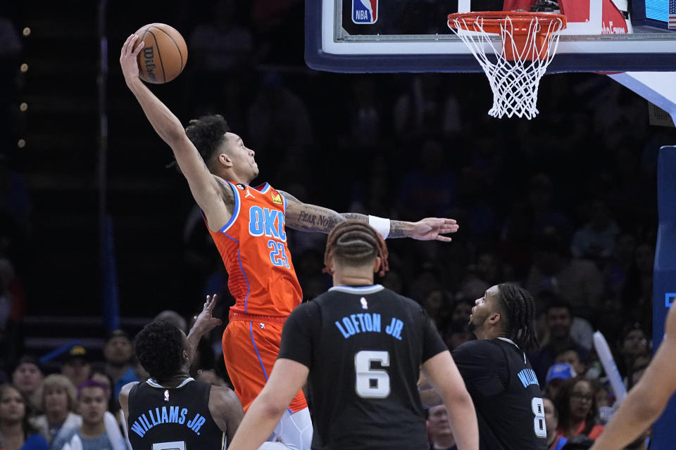 Oklahoma City Thunder guard Tre Mann (23) goes up for a dunk in front of Memphis Grizzlies guard Vince Williams Jr., left, forward Kenneth Lofton Jr. and forward Ziaire Williams (8) in the second half of an NBA basketball game Sunday, April 9, 2023, in Oklahoma City. (AP Photo/Sue Ogrocki)