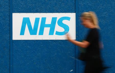 A woman passes an NHS sign at The Royal London Hospital in London, Britain May 13, 2017. REUTERS/Neil Hall/File Photo