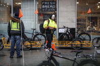 Delivery workers wearing protective gloves and face masks due to coronavirus concerns prepare to work outside a Whole Foods Market on Houston Street, Monday, March 23, 2020, in New York. An order requiring most New Yorkers stay home went into effect Sunday, part of the state's efforts to stem the coronavirus pandemic. (AP Photo/John Minchillo)