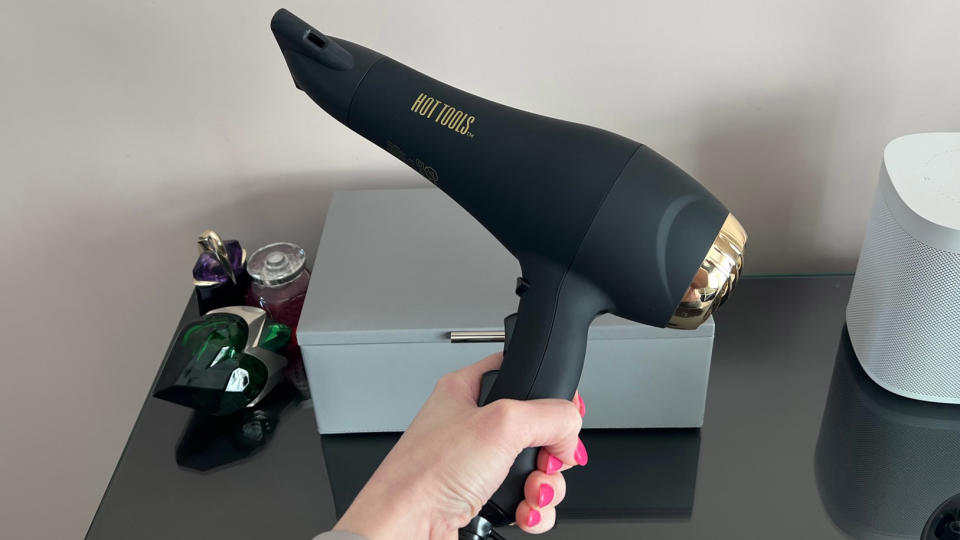 The Hot Tools Pro Signature Salon Ionic AC motor hair dryer being held in a hand with the concentrator nozzle attached