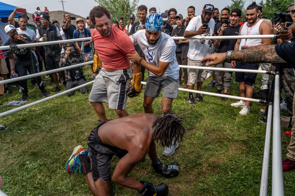 Ronald London, of Battle Creek, is held back by Dwayne Taylor, of Lincoln Park, after London knocked his opponent down as a crowd of fighters and spectators surround a makeshift ring to watch a boxing match during a Pick Your Poison Detroit event in Detroit's Delray neighborhood on Sunday, August 8, 2021.