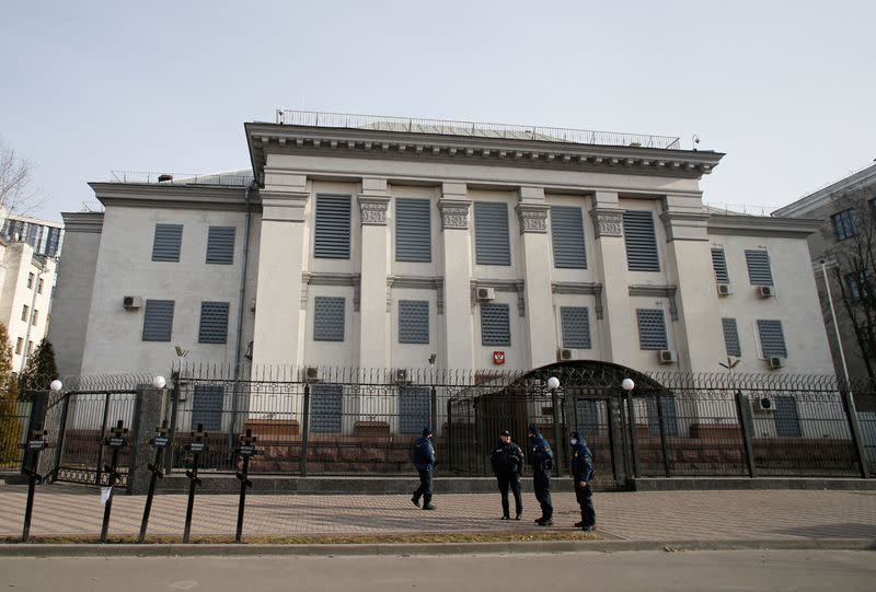 A police officer and members of the Ukrainian National Guard stand in front of the Russian embassy in Kyiv