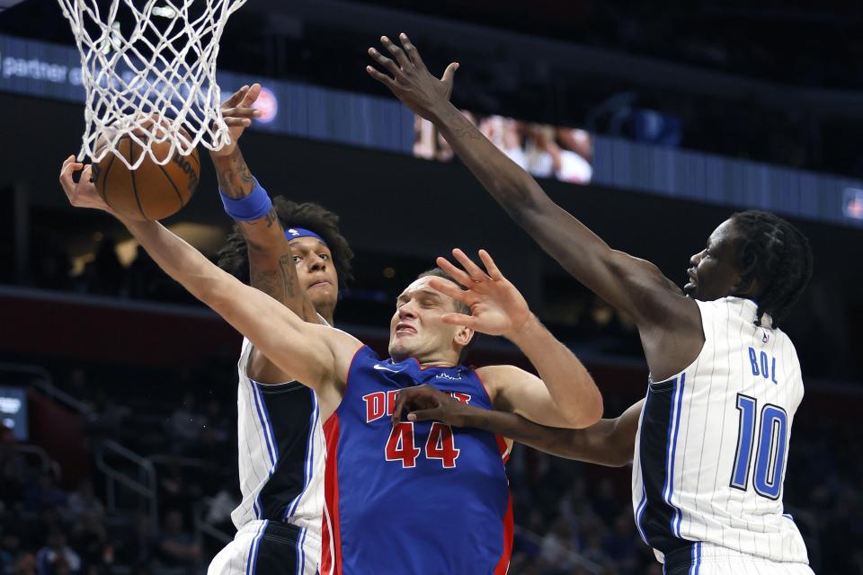 Detroit Pistons forward Bojan Bogdanovic (44) goes to the basket against Orlando Magic forward Paolo Banchero, left, and center Bol Bol (10) during the first half of an NBA basketball game Wednesday, Dec. 28, 2022, in Detroit. (AP Photo/Duane Burleson)