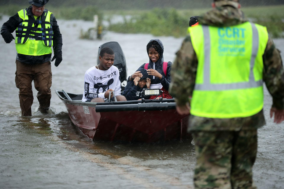 Volunteers from the Civilian Crisis Response Team help rescue three children from their flooded home in James City on Friday.