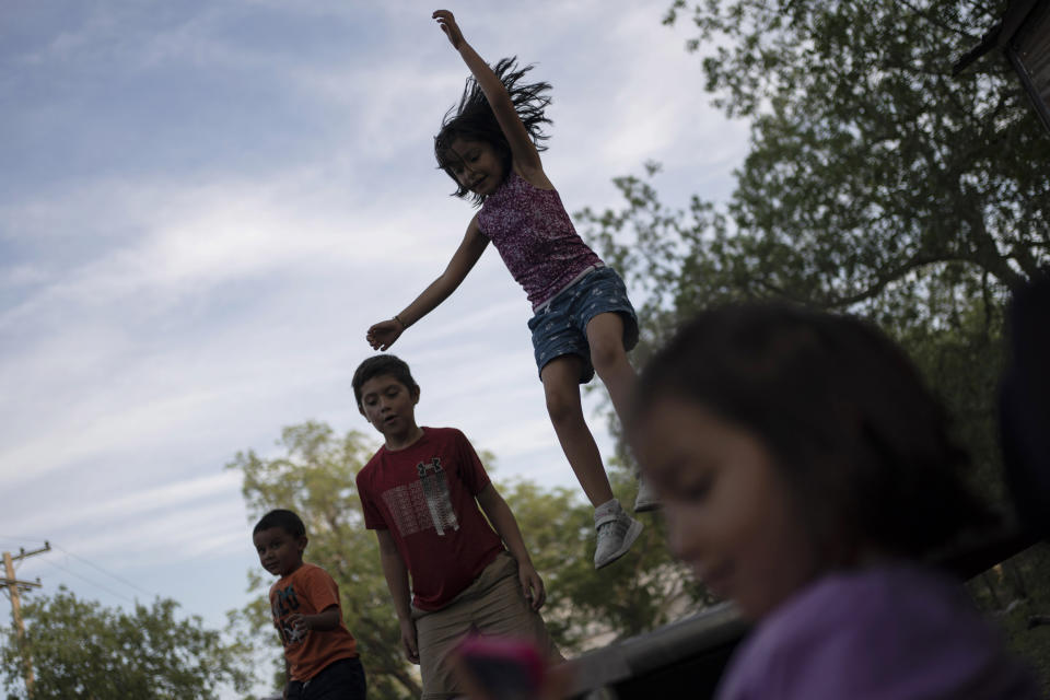 Eight-year-old Jeremiah Lennon, second from left, plays on a trampoline with relatives, Saturday, May 28, 2022, in Uvalde, Texas. The third grader had been in classroom 112, just next to the rooms where the shooter holed up. The kids in his class sat on the ground in the corner, as quiet as they could be, he said. The gunman tried to get in but the door was locked. Jeremiah said he was mad at first, because they were missing recess. He was also terrified: "I was scared I would get shot, my friends would get shot." (AP Photo/Wong Maye-E)