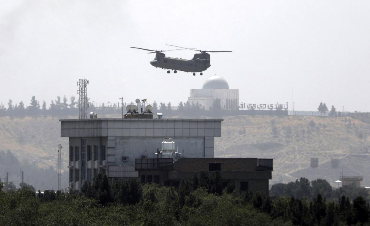 A U.S. Chinook helicopter flies over the U.S. Embassy in Kabul, Afghanistan, on Sunday, Aug. 15, 2021. Helicopters were landing at the U.S. Embassy and diplomatic vehicles were leaving the compound amid the Taliban advance on the Afghan capital. (AP Photo/Rahmat Gul)