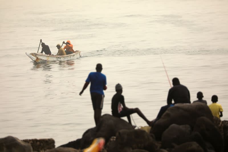 Fishermen are pictured on their pirogue as dust carried by winds from the Sahara Desert shrouds Dakar