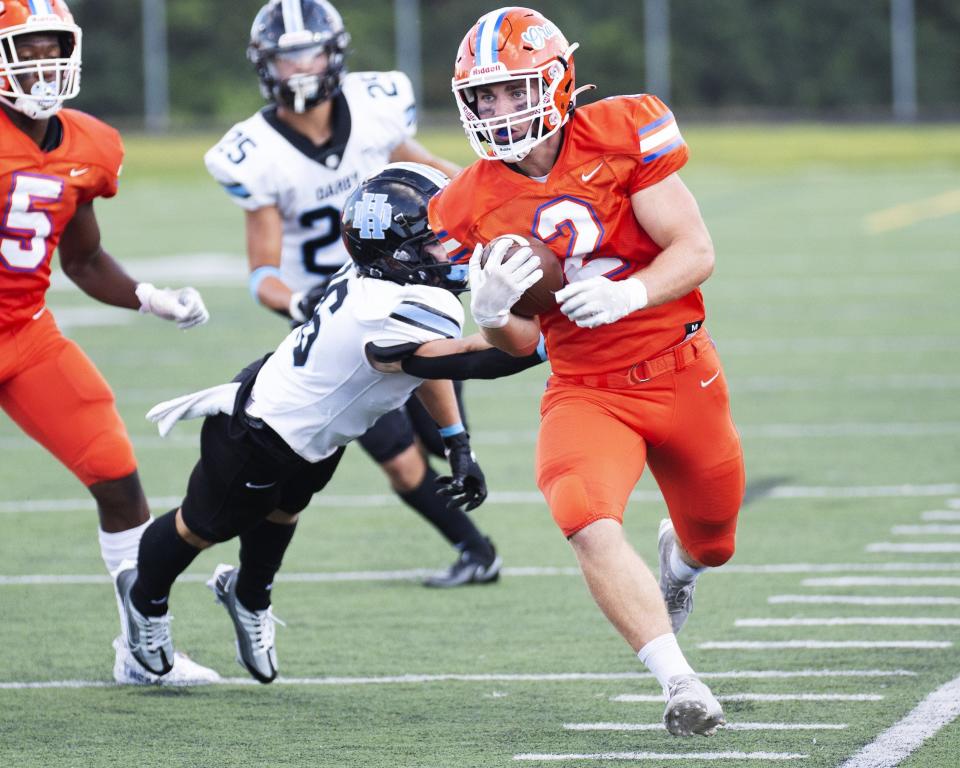 Olentangy Orange's Bobby Ogles shakes off a Hilliard Darby defender en route to a touchdown on Aug. 19.