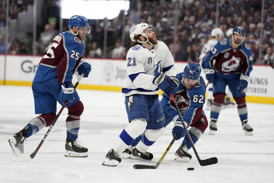 Tampa Bay Lightning center Brayden Point (21) is defended by Colorado Avalanche left wing Artturi Lehkonen (62) during the third period of Game 1 of the NHL hockey Stanley Cup Final on Wednesday, June 15, 2022, in Denver. (AP Photo/John Locher )