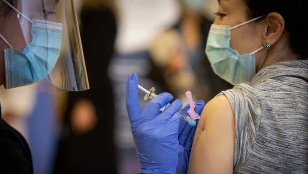 Minjung Choi, associate director of care at Fountain View Care Community, gets a dose of COVID-19 vaccine at a clinic in Toronto on Dec. 15, 2020. Just over half of Ontario long-term care workers have been inoculated so far, according to the province. (Evan Mitsui/CBC - image credit)