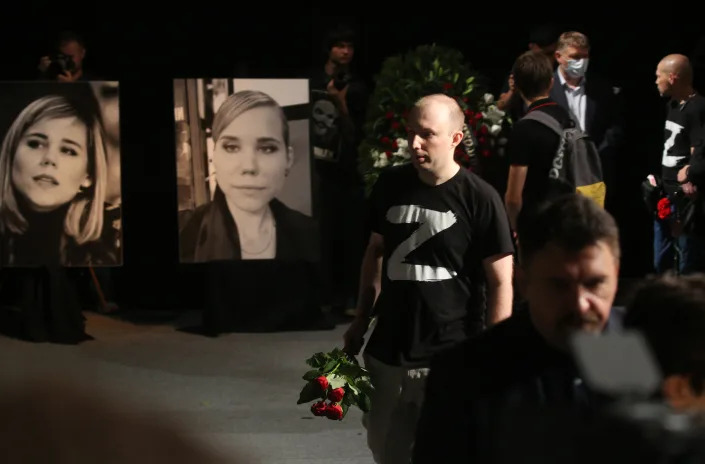 A man wearing a T-shirt with the letter Z holds flowers at a memorial ceremony for Darya Dugina.