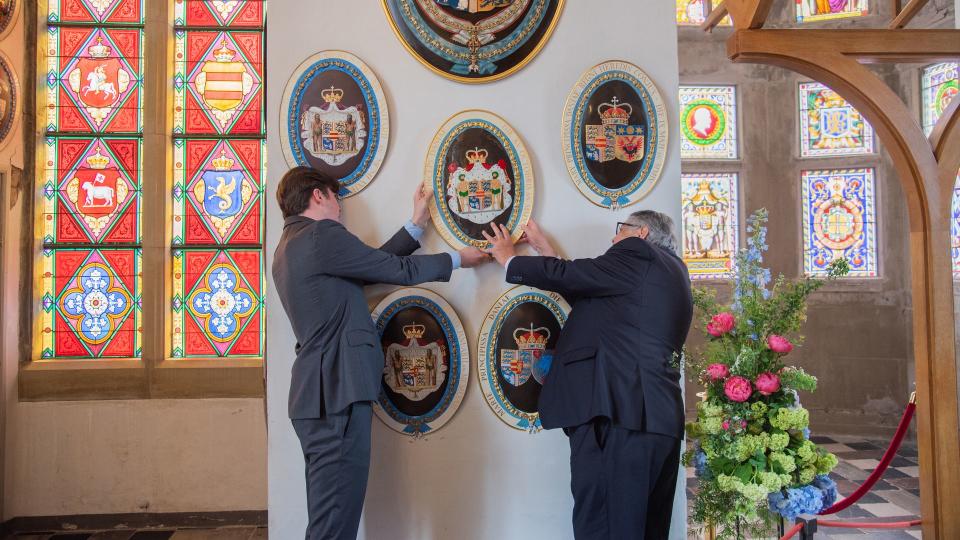 Prince Christian helps to put coat of arms on the wall