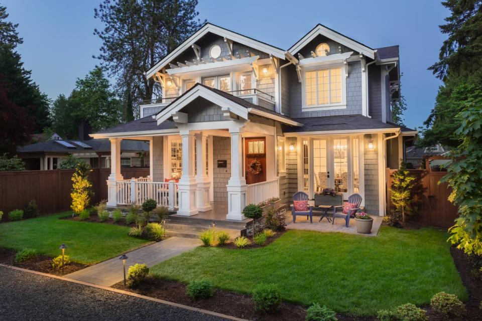 large modern house lit up at night with clear straight path in yard to front porch