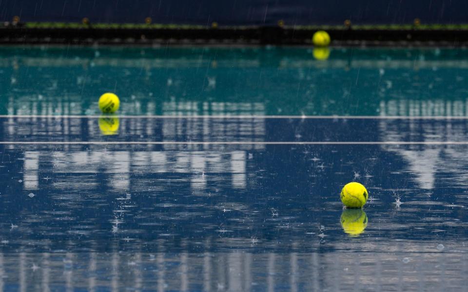 Practice balls lay strewn on a rain-soaked competition court during an hours-long rain delay at the Miami Open tennis tournament, Friday, March 22, 2024, in Miami Gardens