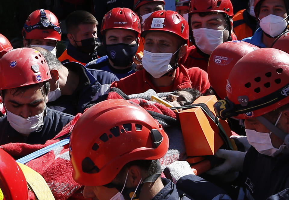 Medics and rescue personnel carry into an ambulance an injured person from the debris of a collapsed building in Izmir, Turkey, Saturday, Oct. 31, 2020. Rescue teams on Saturday ploughed through concrete blocs and debris of eight collapsed buildings in Turkey's third largest city in search of survivors of a powerful earthquake that struck Turkey's Aegean coast and north of the Greek island of Samos, killing dozens of people. Hundreds of others were injured. (AP Photo/Emrah Gurel)