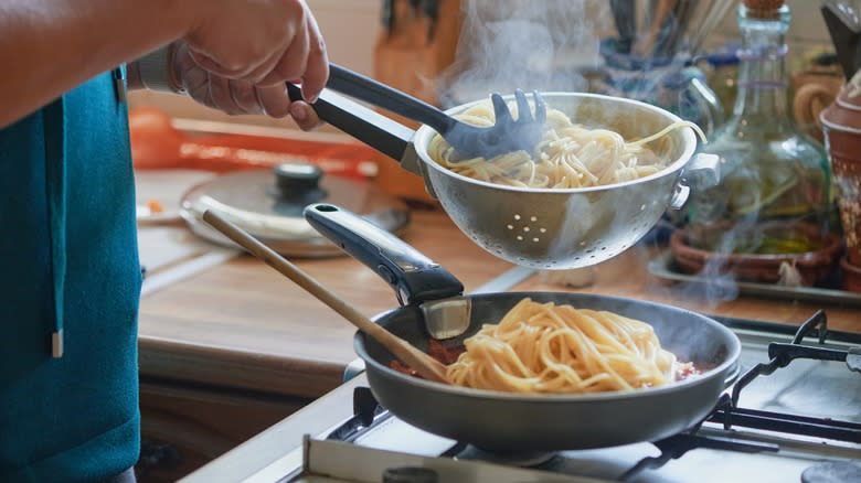 adding pasta to sauce