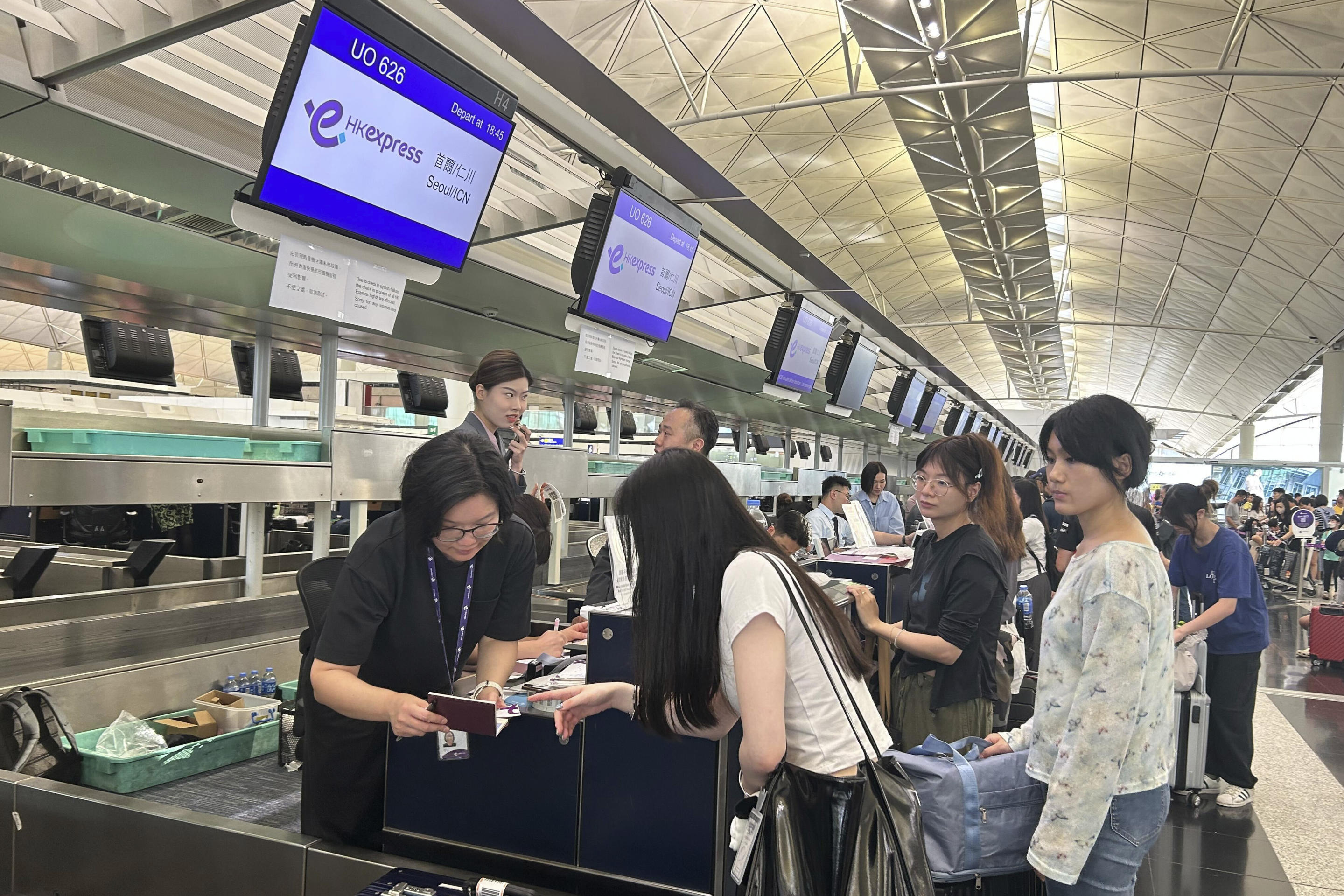 Passengers queue for manual check-in at Hong Kong International Airport.