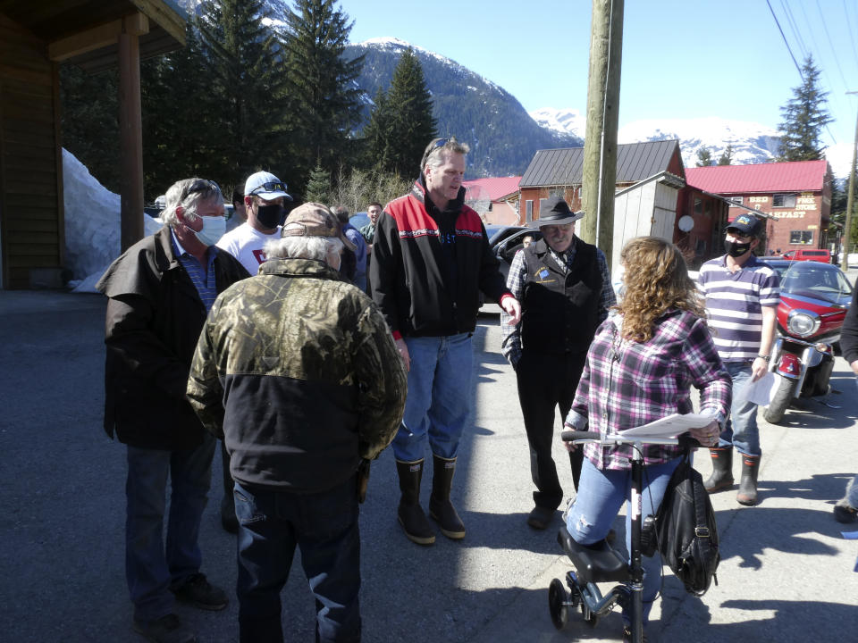 Alaska Gov. Mike Dunleavy, center, meets with people near an outdoor COVID-19 vaccination clinic in Hyder, Alaska, on Thursday, April 22, 2021. Dunleavy said Alaska is in a fortunate position with its vaccine supply and he wants to share vaccines with people across the border in Stewart, British Columbia, a community that has close ties to Hyder. (AP Photo/Becky Bohrer)