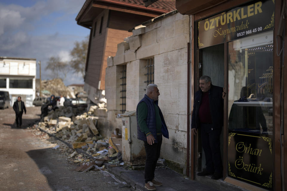 Orhan Ozturk, right, stands at the entrance of his jewellery shop as he speak with a friend in Antakya, southern Turkey, Thursday, Jan. 11, 2024. Ozturk was able to open his shop after rubble out front was cleared but hasn’t had many customers. (AP Photo/Khalil Hamra)