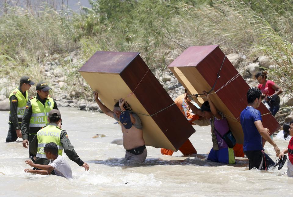 People carry their belongings while crossing the Tachira river border with Venezuela into Colombia, near Villa del Rosario village