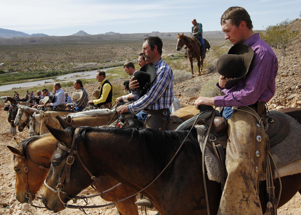 Kholten Gleave, right, of Utah, pauses for the National Anthem outside of Bunkerville , Nev. while gathering with other supporters of the Bundy family to challenge the Bureau of Land Management on April 12, 2014. (AP Photo/Las Vegas Review-Journal, Jason Bean)