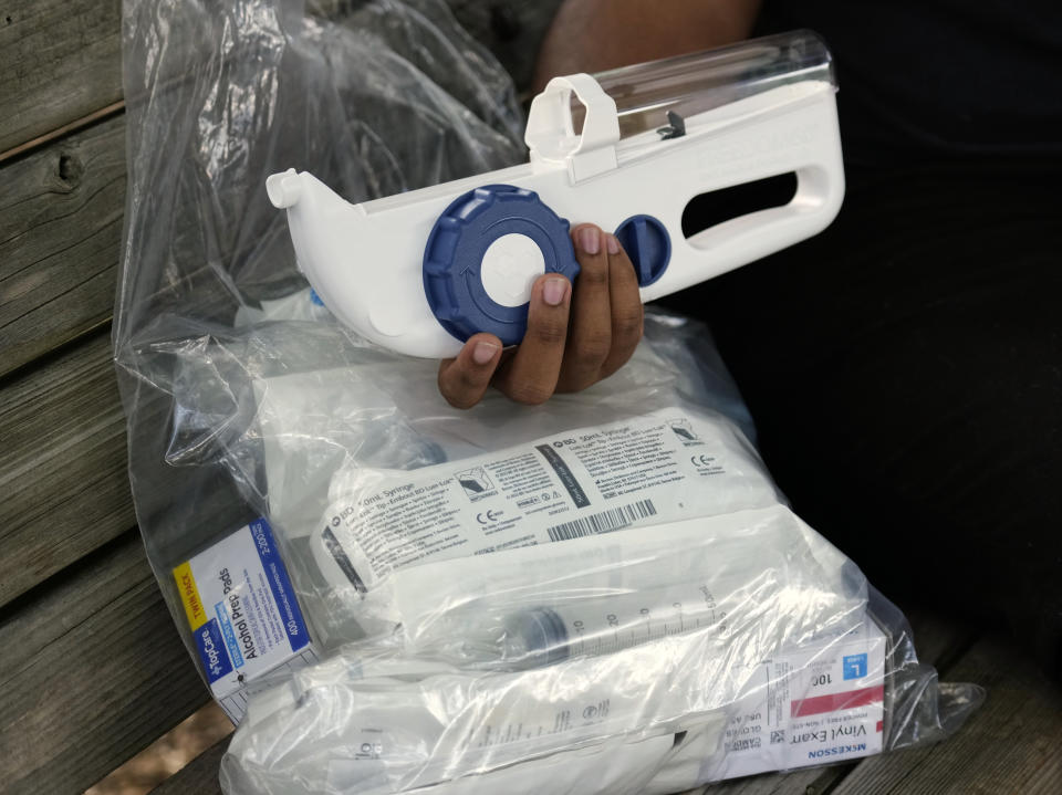 Camden Alderman, 21, who has a rare disease called Wiskott-Aldrich syndrome, holds some of the drugs and medical equipment he uses near his home in Greensboro, N.C., Wednesday, June 12, 2024. (AP Photo/Chuck Burton)