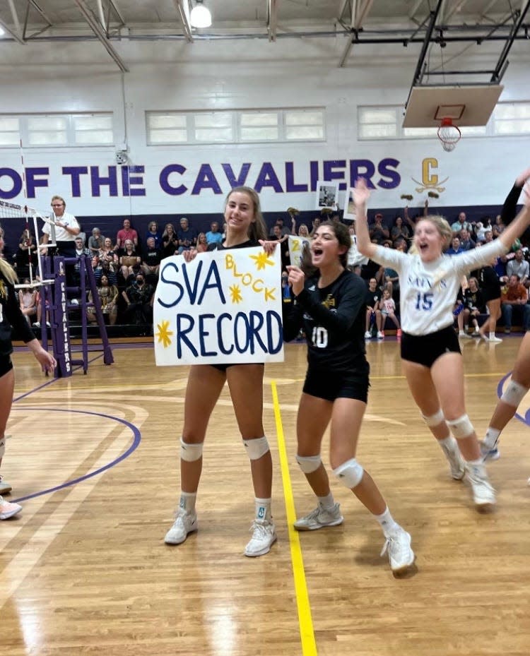 Mattie Lynch ( holding sign) celebrates with teammates after setting the school career record for blocks.