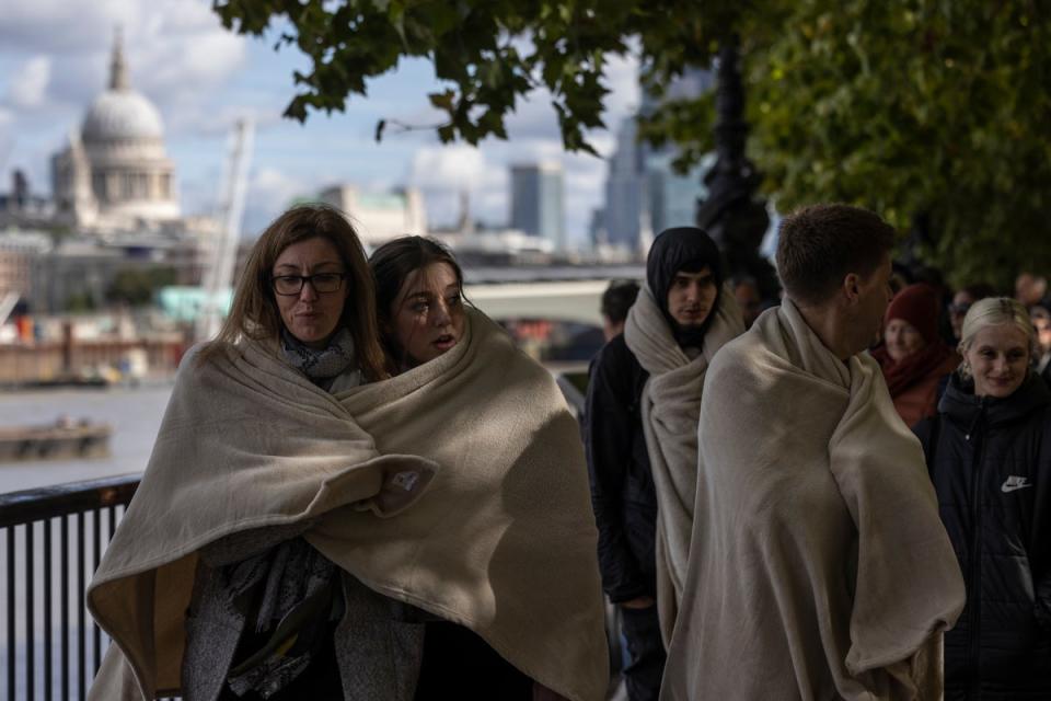 La gente se mantiene caliente acurrucándose bajo mantas mientras espera en la fila para visitar el ataúd de Su Majestad (Getty Images)