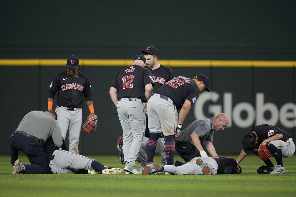 Cleveland Guardians manager Stephen Vogt (12), players and staff check on Cleveland Tyler Freeman, on ground left, and Brayan Rocchio, on ground right, after the two collided chasing after a fly out by Texas Rangers' Adolis Garcia in the fifth inning of a baseball game, Tuesday, May 14, 2024, in Arlington, Texas. Freeman cauhght the fly out. (AP Photo/Tony Gutierrez)