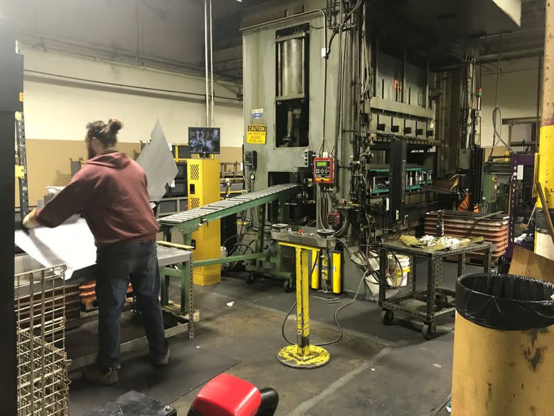 An operator transferrs steel shelf after being stamped out in punch press at Tennsco's factory in Dickson