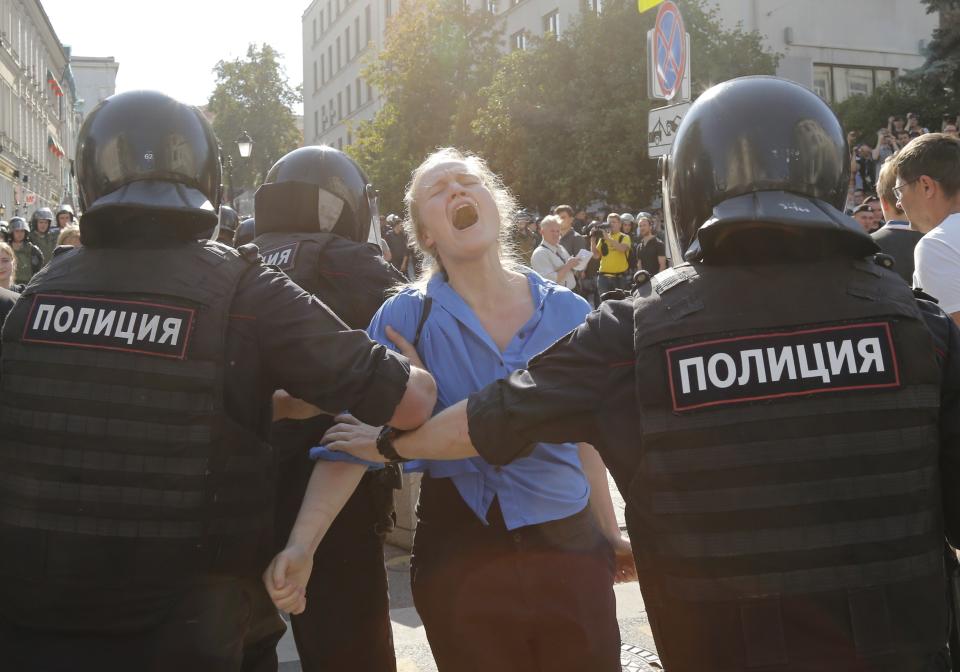 Police officers detain a woman during an unsanctioned rally in the center of Moscow, Russia, Saturday, July 27, 2019. Russian police are wrestling with demonstrators and have arrested hundreds in central Moscow during a protest demanding that opposition candidates be allowed to run for the Moscow city council. (AP Photo/Alexander Zemlianichenko)