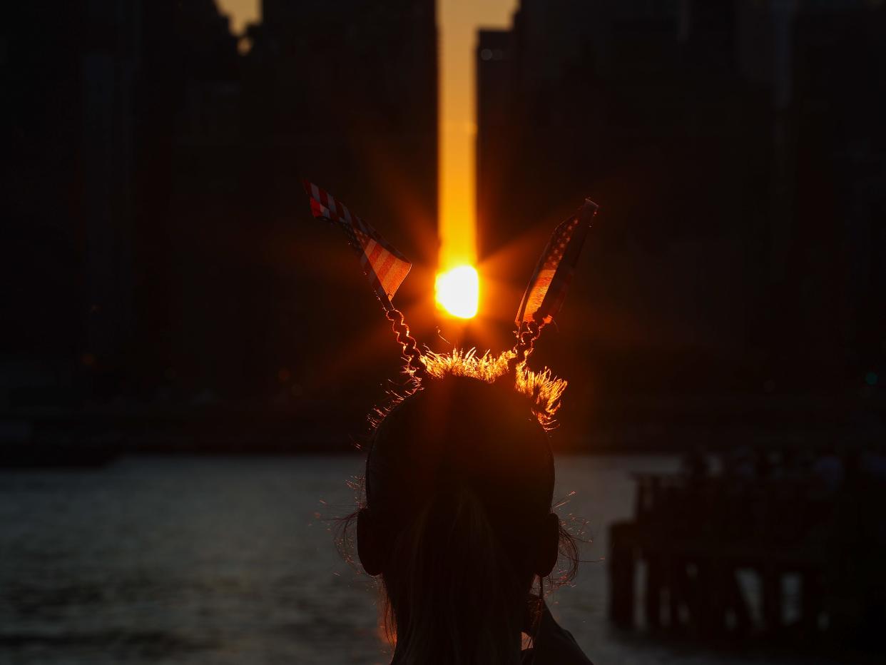 Silhouette of person with American flag headband in front of sunset.