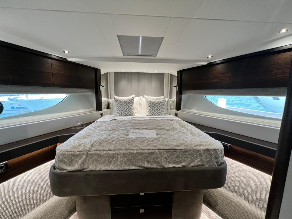 A bedroom at the bow of the lower deck of a Sunseeker 76 yacht. The double bed has grey linen.