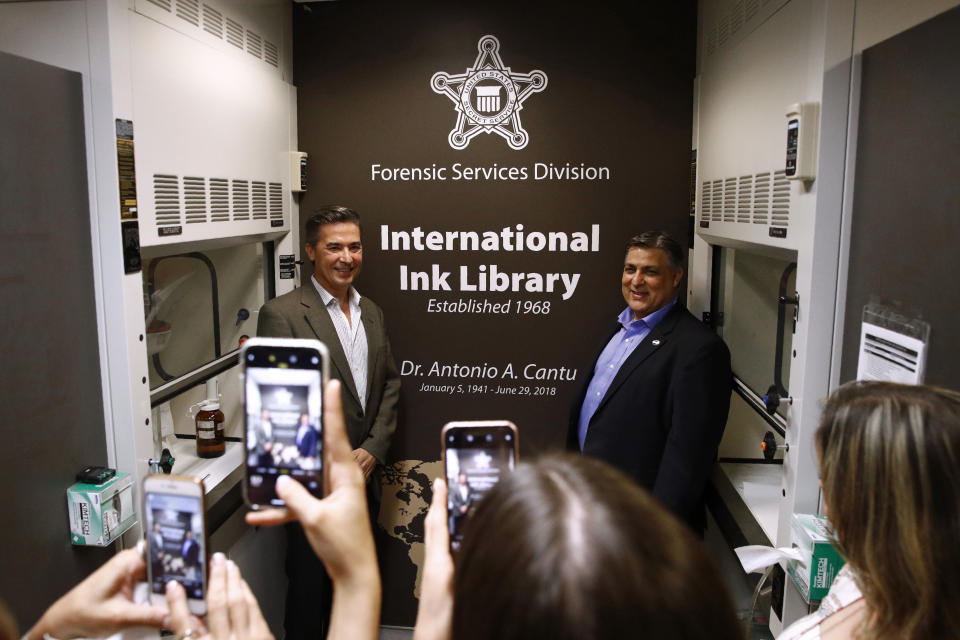 In this June 27, 2019 photo, Vidal Cantu, left, and Arnold Cantu pose for photos in the International Ink Library, which was dedicated in remembrance of their uncle, former U.S. Secret Service chief chemist Antonio Cantu, during a visit to the Secret Service headquarters building in Washington. (AP Photo/Patrick Semansky)