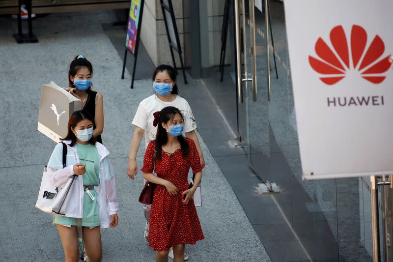 FILE PHOTO: Women walk past a Huawei store at a shopping complex in Beijing