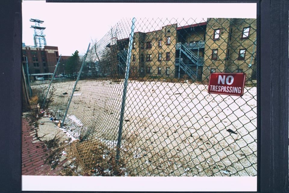 A vacant lot is surrounding by fencing with "no trespassing" signs